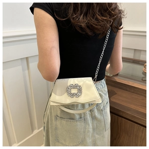 Close-up of cream square crossbody bag featuring a large rhinestone buckle and chain strap