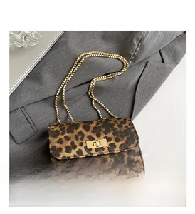 Detail view of the leopard print leather texture and golden metal chain on a crossbody bag