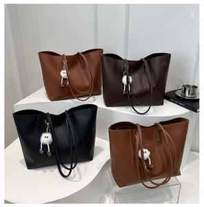 Minimalist tote bags in various brown shades with plush charms on a tiered display
