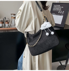 Black suede tote bag with metal chain strap and white plush cloud charm on a model