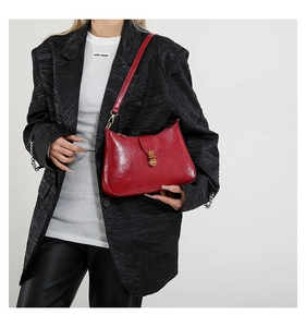 Détail d'un sac hobo rouge en cuir verni vintage avec un fermoir doré classique