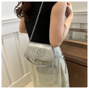 Silver metallic square bag featuring crystal buckle detail and chain strap shown on model