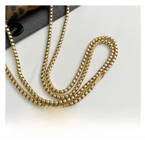 Close-up of high-gloss gold box chain strap with round spring lobster hooks for bags