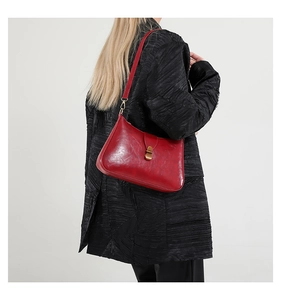 Vue détaillée du cuir huilé rouge vintage et de la boucle en bronze sur le sac à main