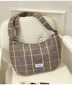 Detail of checkered hobo bag in brown houndstooth wool with a white label on a chair