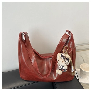 Detail view of large dark red oil wax leather tote bag with stylish leopard doll pendant