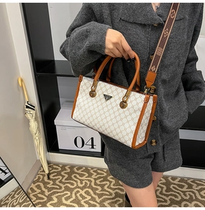 Detail of retro tote bag with brown monogram pattern and wide woven shoulder strap