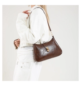Vue latérale d'un sac hobo vintage marron foncé avec fermoir rotatif en bronze sur modèle