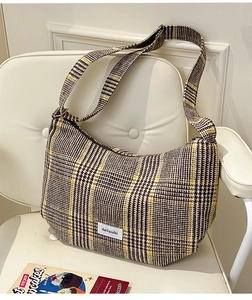 Detail of the brown plaid texture and woven logo label on the wool crossbody bag