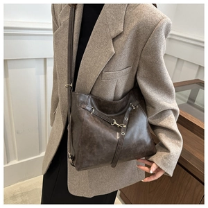Detail einer dunkelbraunen Vintage-Lederschultertasche mit Nieten und Riemen-Akzenten