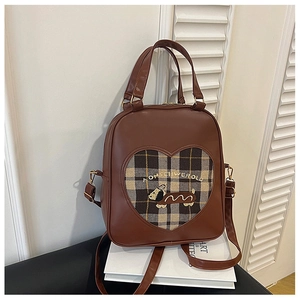 Detail view of brown leather backpack featuring heart cutout with plaid puppy embroidery