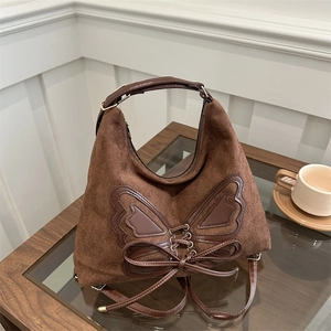 Vintage brown suede hobo bag with bow tie ribbon and gold hardware in a cafe setting