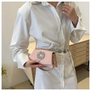Detail of light pink mini flap bag featuring a luxury rhinestone buckle and silver chain