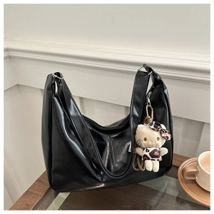 Detailed view of large black shiny leather hobo bag with plush leopard cat charm