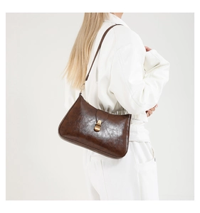 Vue détaillée d'un sac demi-lune vintage marron foncé avec boucle dorée et cuir brillant