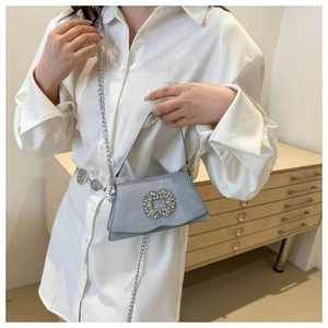 Close-up of the square rhinestone buckle and chain detail on this blue fashion handbag