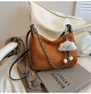 Detailed texture of brown suede bag with metal chain strap and cloud plush charm