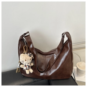 Detail view of large dark brown tote bag with glossy leather finish and plush pendant