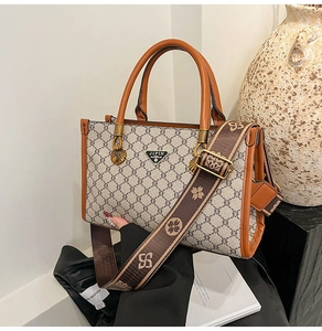 Detail of vintage monogram tote bag with brown leather handles and a patterned wide strap