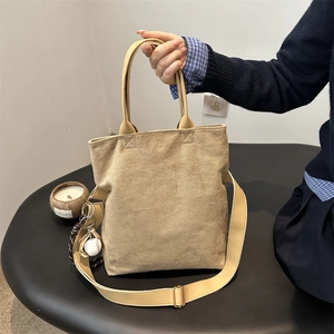 Light brown suede tote bag with shoulder strap and stylish baseball charm for women