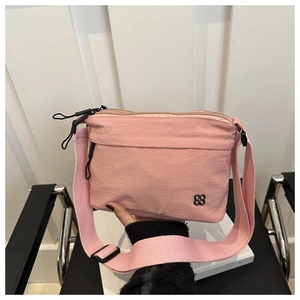 Pink nylon crossbody bag with zipper pockets and adjustable fabric shoulder strap