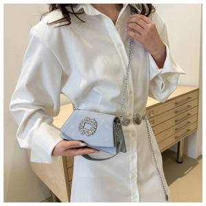Close-up of a light blue mini crossbody bag with a large sparkling crystal square buckle