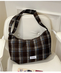 Close-up of retro plaid wool fabric and brand woven label on the brown shoulder bag