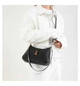 Détail du sac demi-lune noir mat avec fermoir doré et bandoulière en cuir marron