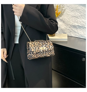 Detail of trendy leopard print crossbody bag with golden chain strap on a model