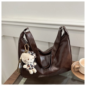 Detail of dark brown tote bag with vertical stitching and cute plush pendant charm