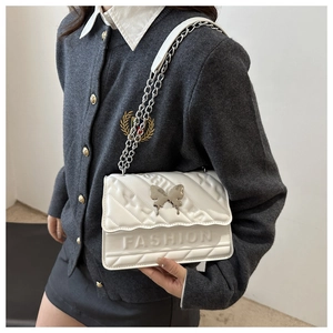 Détail du sac bandoulière blanc matelassé avec boucle papillon argentée et chaîne