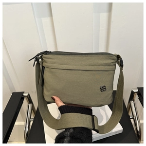 Close-up of olive green nylon crossbody bag with silver clover logo and wide strap