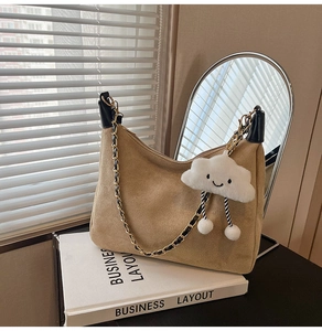 Close-up of khaki suede hobo bag featuring a plush cloud charm and gold chain strap