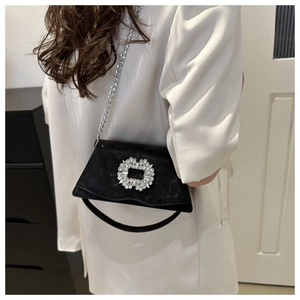 Detail view of stylish black suede handbag featuring a large crystal-encrusted square buckle