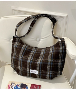 Close-up of vintage brown plaid texture and woven label on wool dumpling shoulder bag