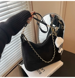 Close-up of black suede hobo bag with gold chain and white plush cloud charm detail