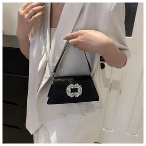 Detail of a black velvet handbag featuring a luxury sparkling rhinestone square buckle