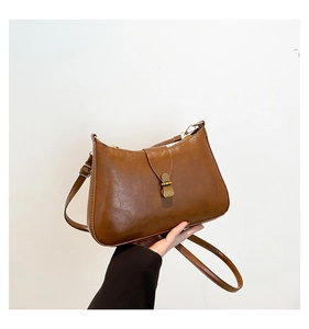 Détail du sac croissant marron vintage avec texture plissée et fermoir en métal bronzé
