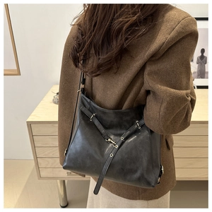 Detail einer schwarzen Vintage-Ledertasche mit Goldschnalle und Umhängegurt