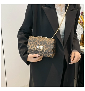 Detail of leopard print crossbody bag with gold chain strap worn over a black blazer