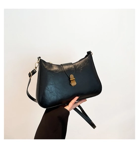 Détail du sac croissant noir avec boucle dorée polie et bandoulière réglable pratique