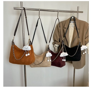 Detail of four colorful corduroy hobo bags with plush cloud charms on a display stand