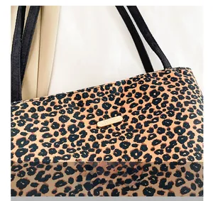Detailed close-up of leopard print tote bag with gold logo plate and black strap