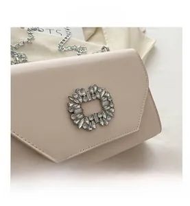 Detail of a pink leather crossbody bag with a large sparkling rhinestone buckle and silver chain