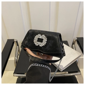 Close-up of luxury black velvet handbag featuring a sparkling square crystal buckle detail