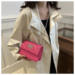 Vue détaillée du sac matelassé magenta avec papillon argenté et bandoulière chaîne