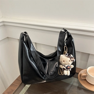 Chic black oversized faux leather tote bag featuring a cute leopard print plush charm