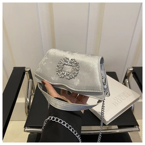 Detail of silver velvet evening bag featuring a radiant crystal brooch and chain strap