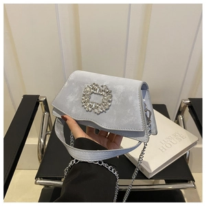 Detail of light blue crossbody bag featuring a crystal buckle and silver chain strap