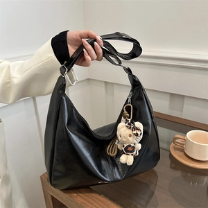 Fashionable black glossy crescent hobo tote bag with a plush cat charm accessory